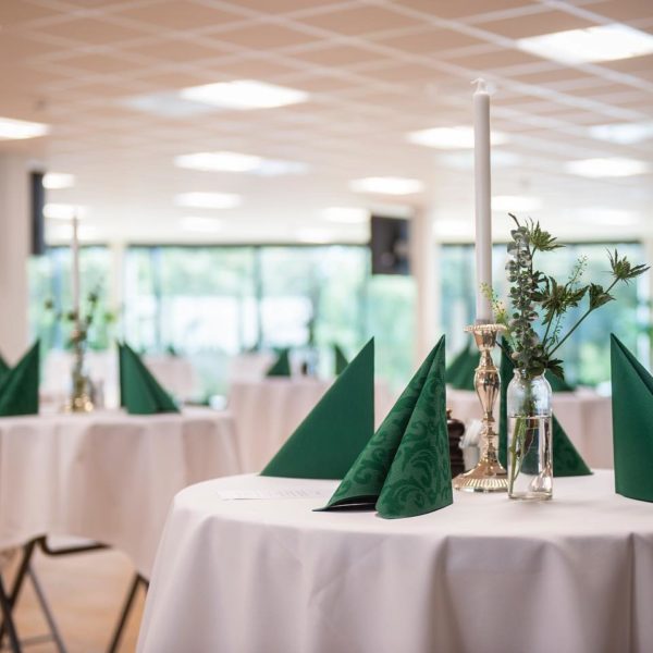 Selskabslokaler i Esbjerg. Elegant dækkede stå-borde med grønne servietter og blomsterdekorationer til event.