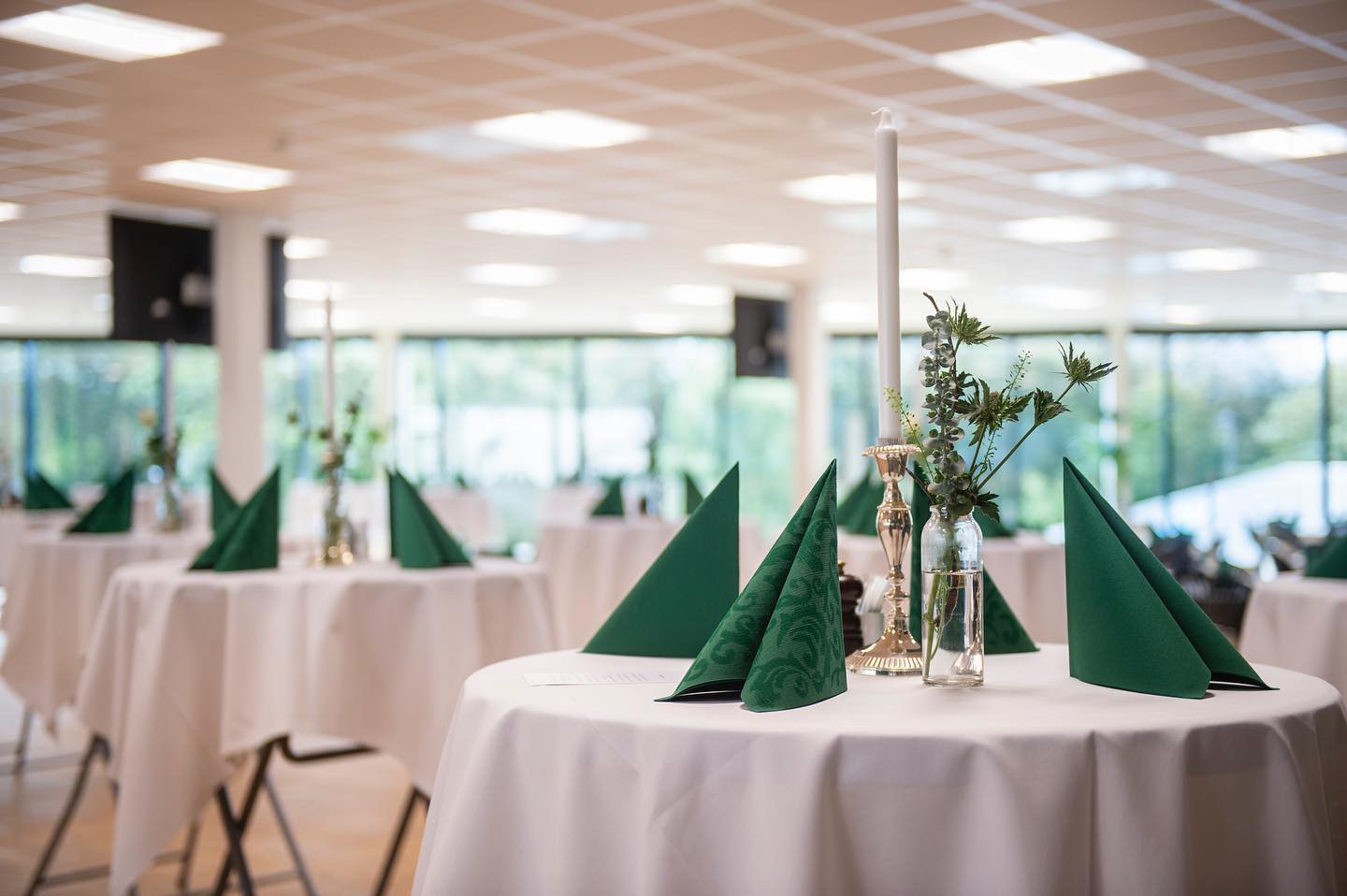 Selskabslokaler i Esbjerg. Elegant dækkede stå-borde med grønne servietter og blomsterdekorationer til event.