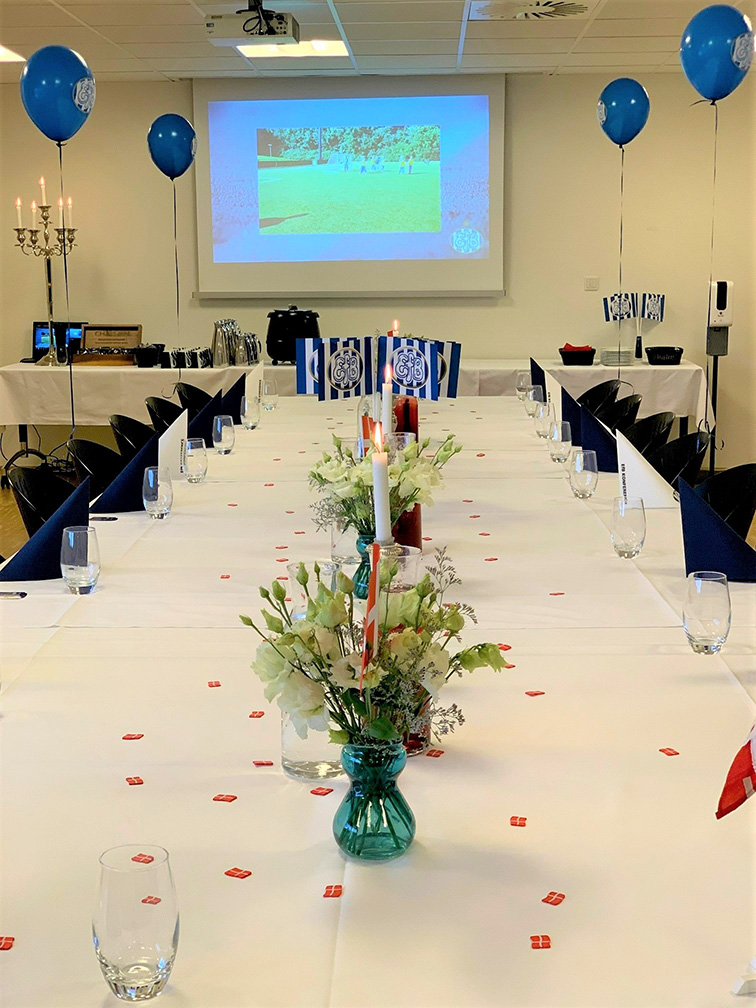 Langt festbord dækket til børnefødselsdag med EfB-balloner, små flag og blomster, mens en fodboldbilleder vises på lærred i baggrunden.