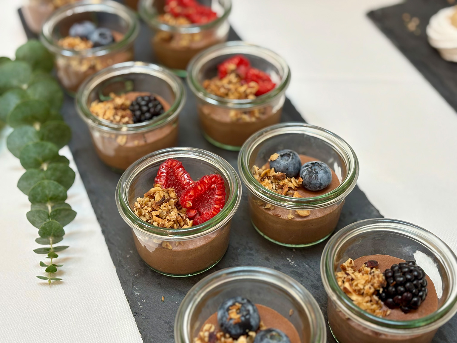 Små portionsglas med chokolademousse pyntet med friske bær og sprød granola – lavet af husets egen konditor.