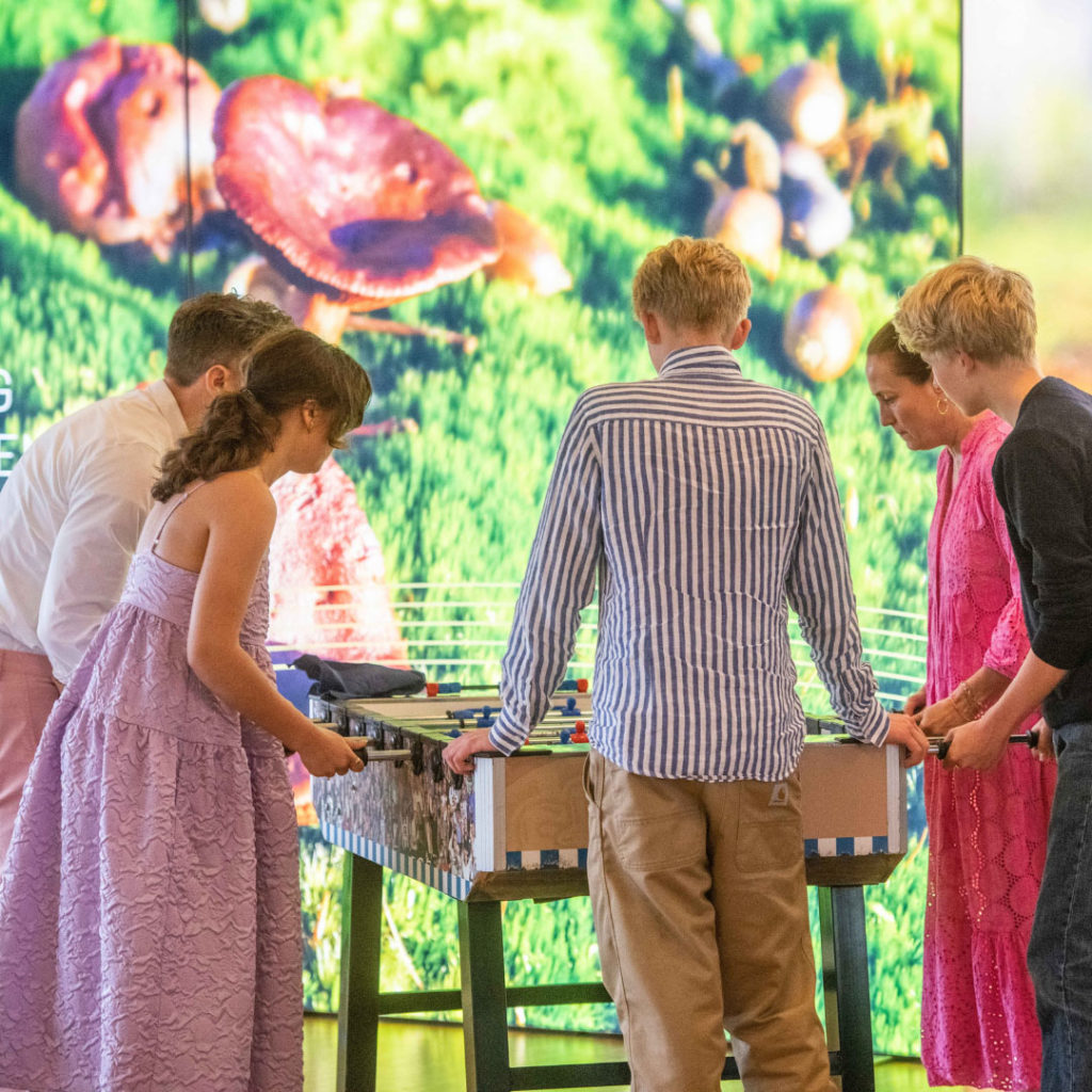 Unge gæster spiller bordfodbold til en konfirmation med farverig baggrund hos Esbjerg Konference & Event.