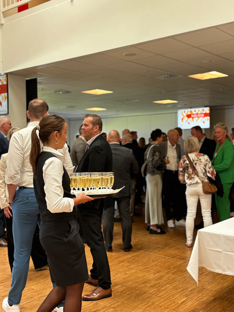 Servitrice serverer velkomstbobler for gæster ved et festligt arrangement i loungen på Blue Water Arena.