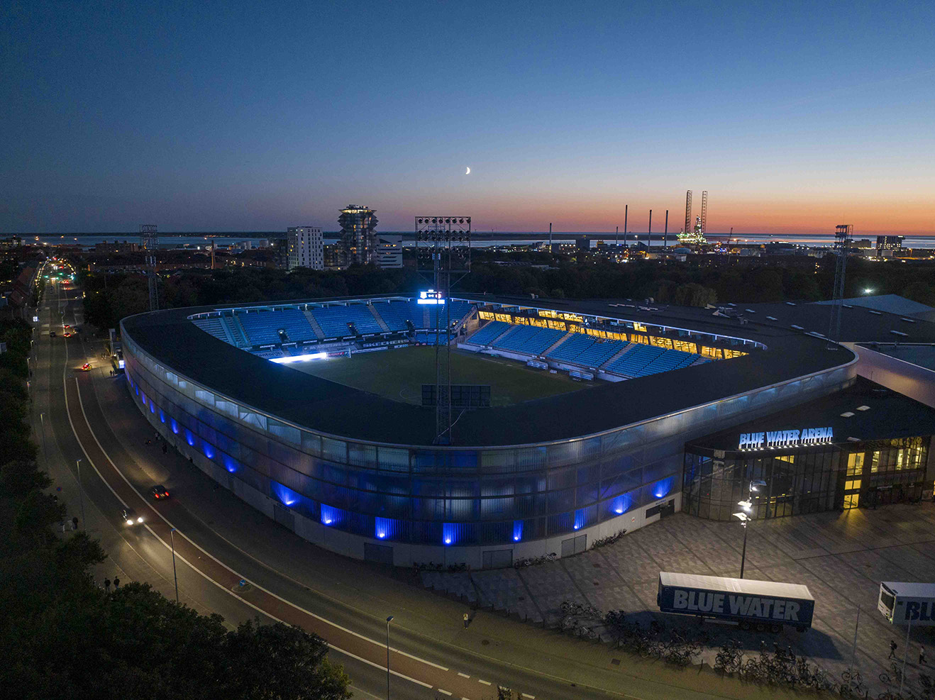 Dronebillede af Blue Water Arena med havnen og solnedgang i baggrunden