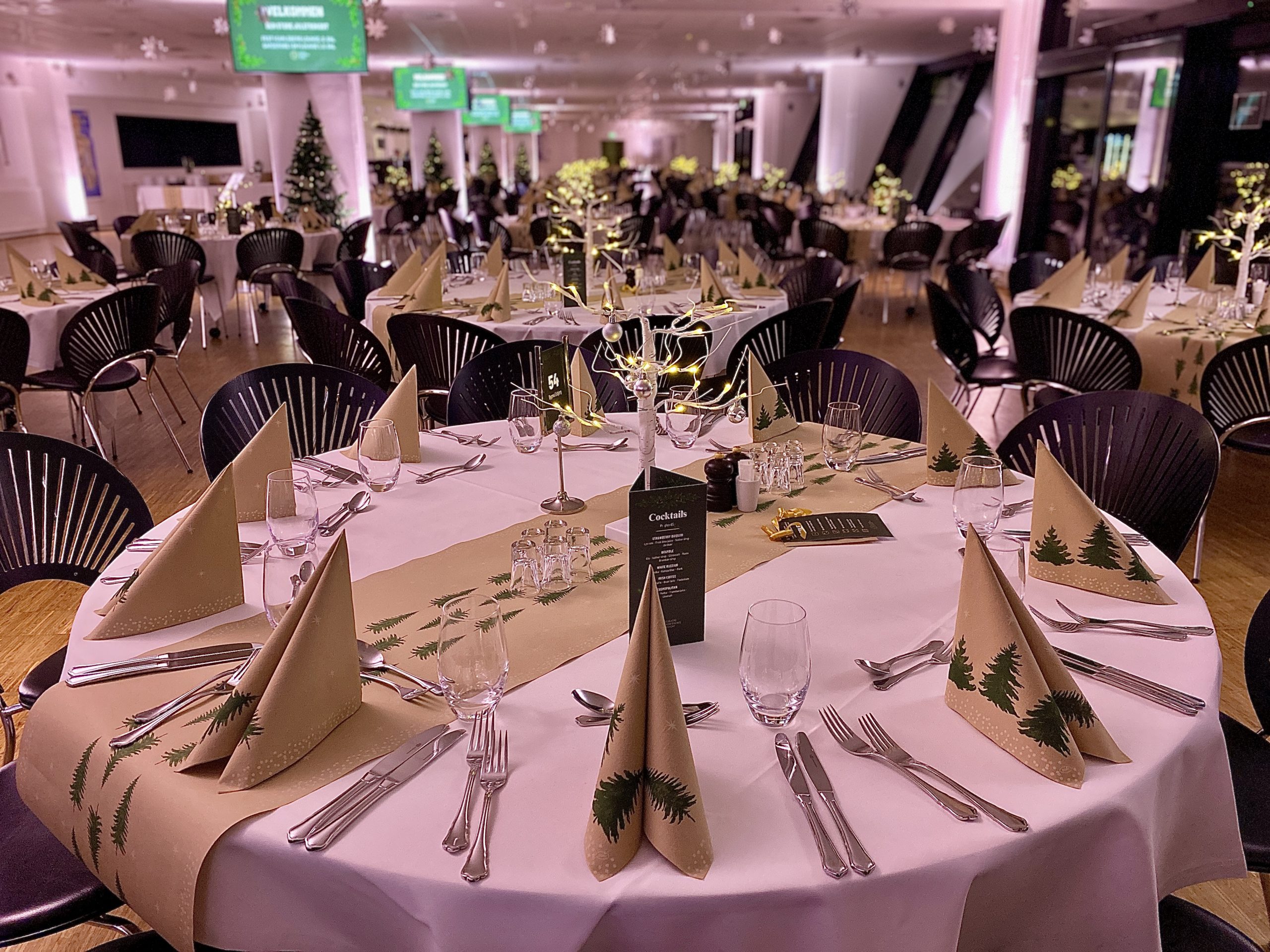 Julepyntede runde borde med grønne servietter, stearinlys og dekorationer til festlig julefrokost hos Esbjerg Konference & Event på Blue Water Arena.