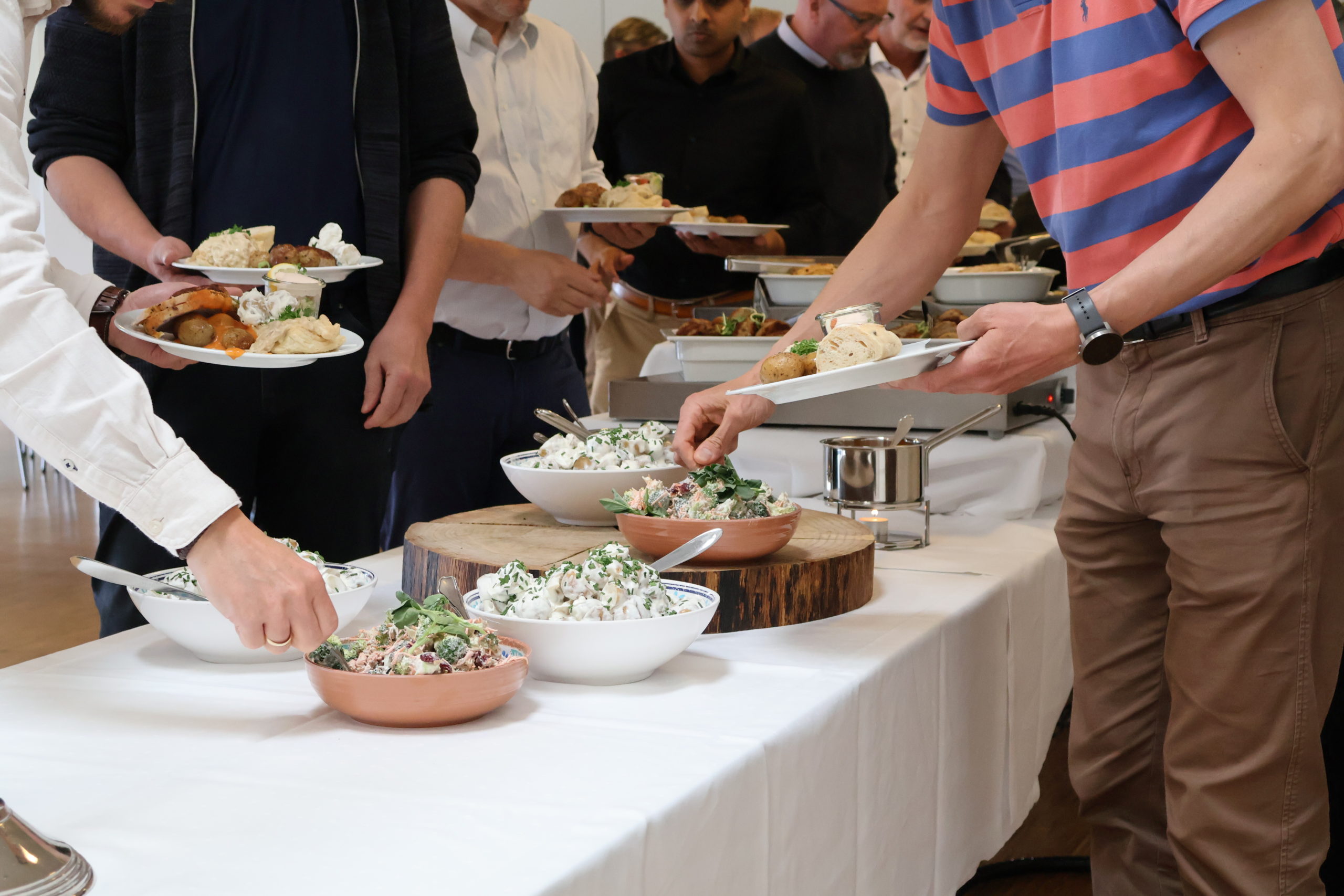 Gæster tager mad fra buffet med salater, kød og brød under frokostarrangement hos Esbjerg Konference & Event.