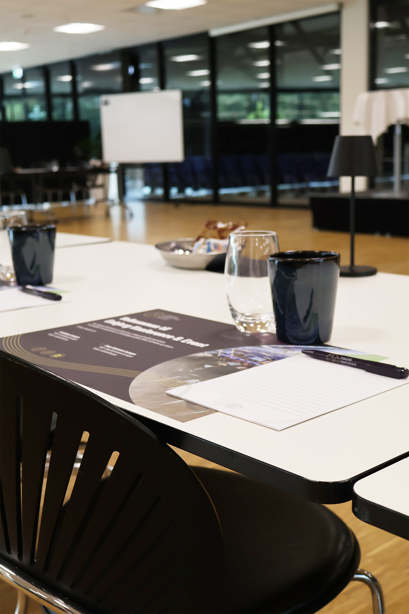 Lyst og indbydende mødelokale med borde dækket med glas, notesblokke og snacks klar til konference i Claus Sørensen Lounge hos Esbjerg Konference & Event.