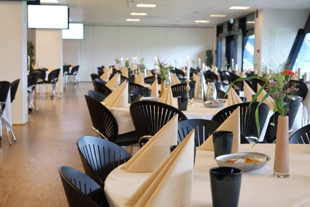 Carlsberg Loungen på Blue Water Arena dækket op med beige servietter, blomster, levende lys, småkager, kaffe og te.