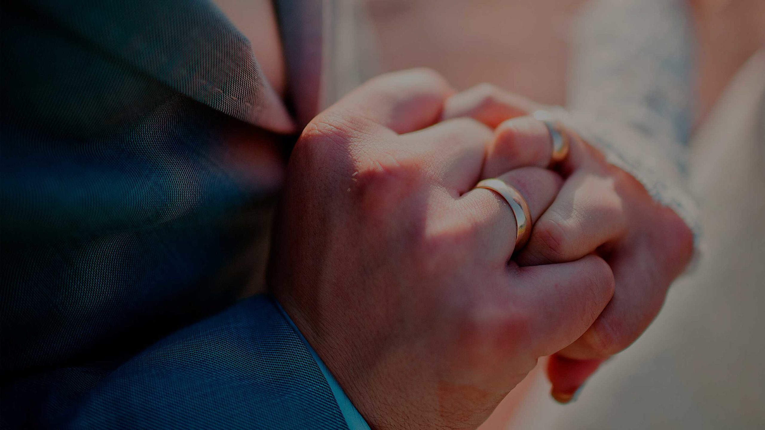 Bryllupsbillede med gommen og bruden der holder i hånd med vielsesringe på hænder