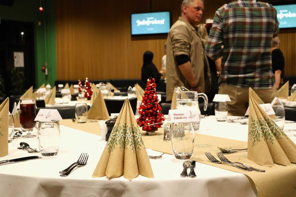 Julefrokost i EfB Caféen med opdækkede borde og røde juletræer