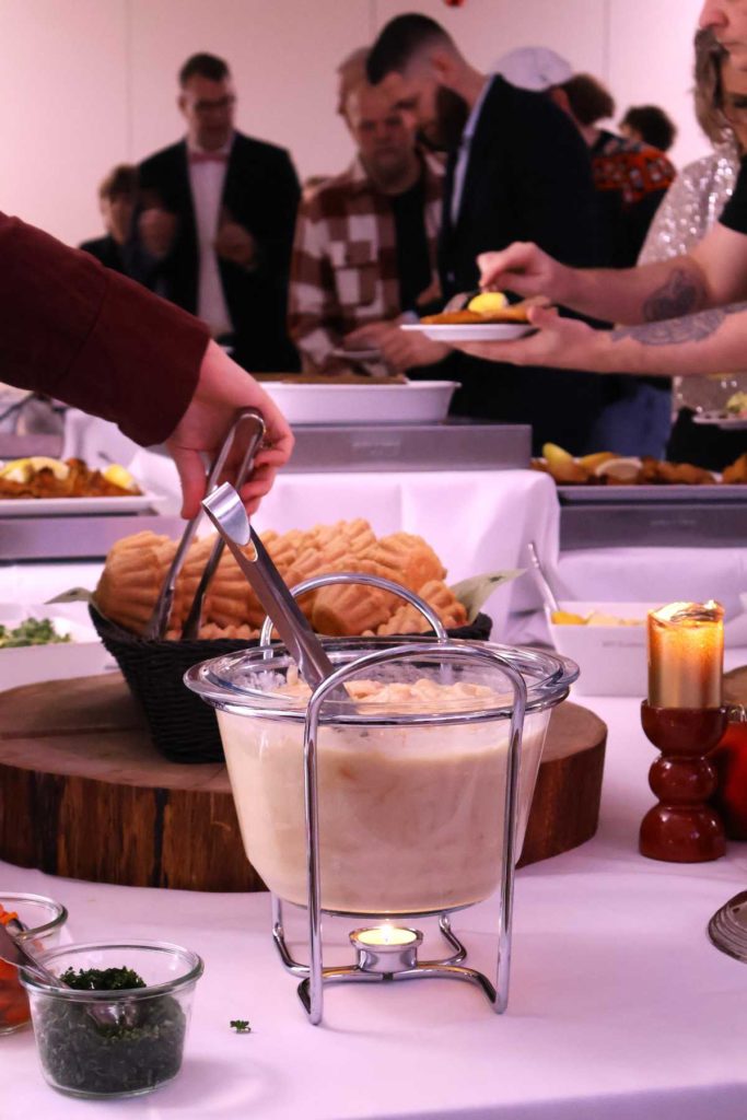 Gæster tager af buffeten til Den Store Julefrokost med tarteletter, fiskefilet og diverse julefrokostretter