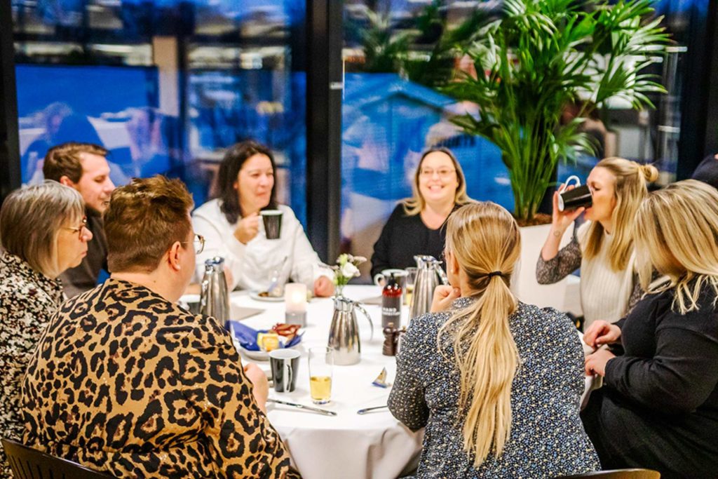 Gæster nyder kaffe og samtale omkring et opdækket bord i hyggelige omgivelser i Claus Sørensen Lounge hos Esbjerg Konference & Event.