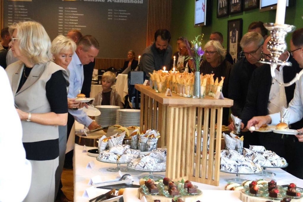 Gæster nyder af receptionsbuffet med små retter i alt sliders og hotdog til tacos og fish and chips fra i EfB Caféen