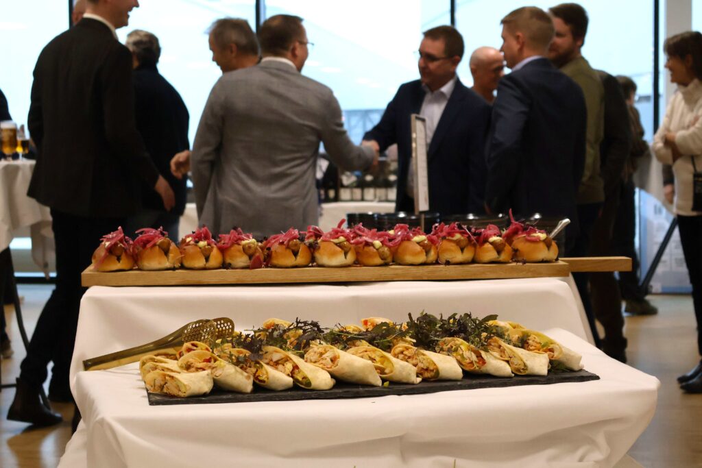 Gæster hilser bagved buffet med gourmet hotdogs og andre små retter til reception