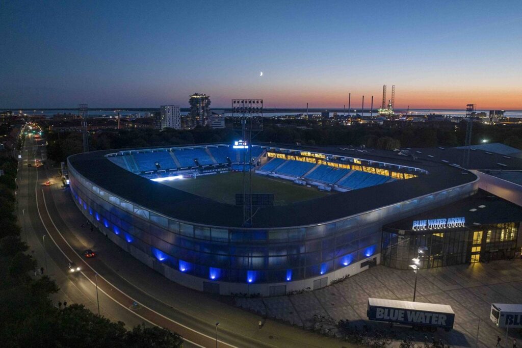 Blue Water Arena dronefoto om aftenen med solnedgang i baggrunden og oplyst stadion