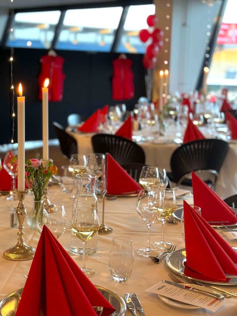 Røde servietter, levende lys og elegant opdækning sætter scenen for en festlig firmaaften med god mad, vin og hyggeligt samvær i Carlsberg Loungen.