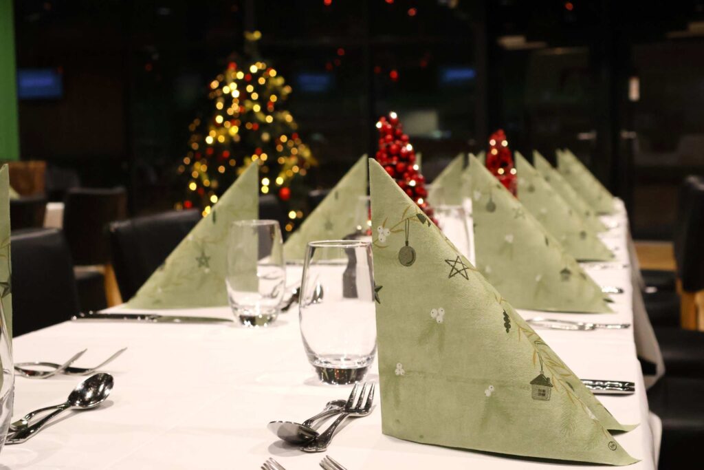 Julefrokost i EfB Caféen med opdækket borde og juletræ i baggrunden