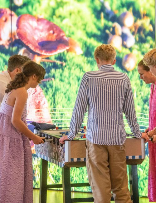 Unge gæster spiller bordfodbold til en konfirmation med farverig baggrund hos Esbjerg Konference & Event.
