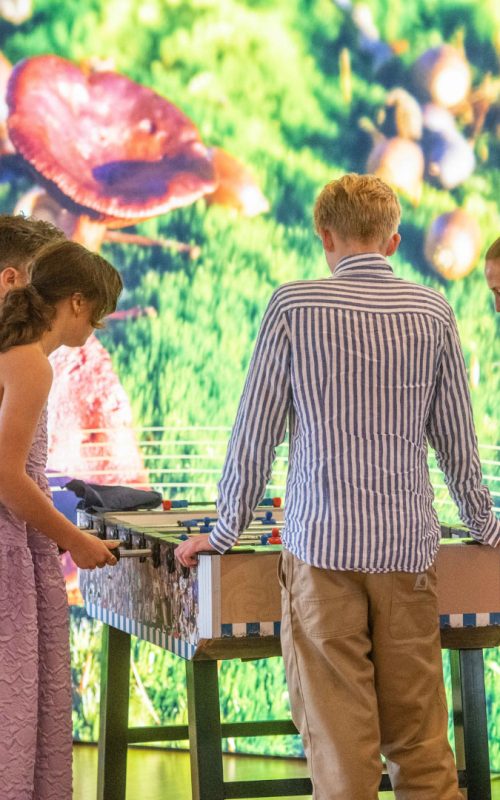 Unge gæster spiller bordfodbold til en konfirmation med farverig baggrund hos Esbjerg Konference & Event.