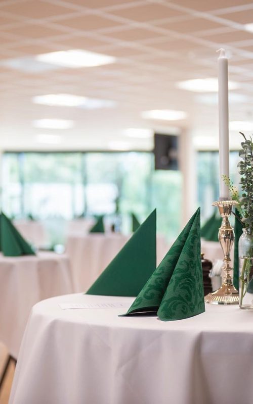 Selskabslokaler i Esbjerg. Elegant dækkede stå-borde med grønne servietter og blomsterdekorationer til event.