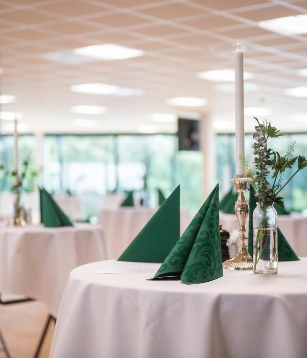 Selskabslokaler i Esbjerg. Elegant dækkede stå-borde med grønne servietter og blomsterdekorationer til event.