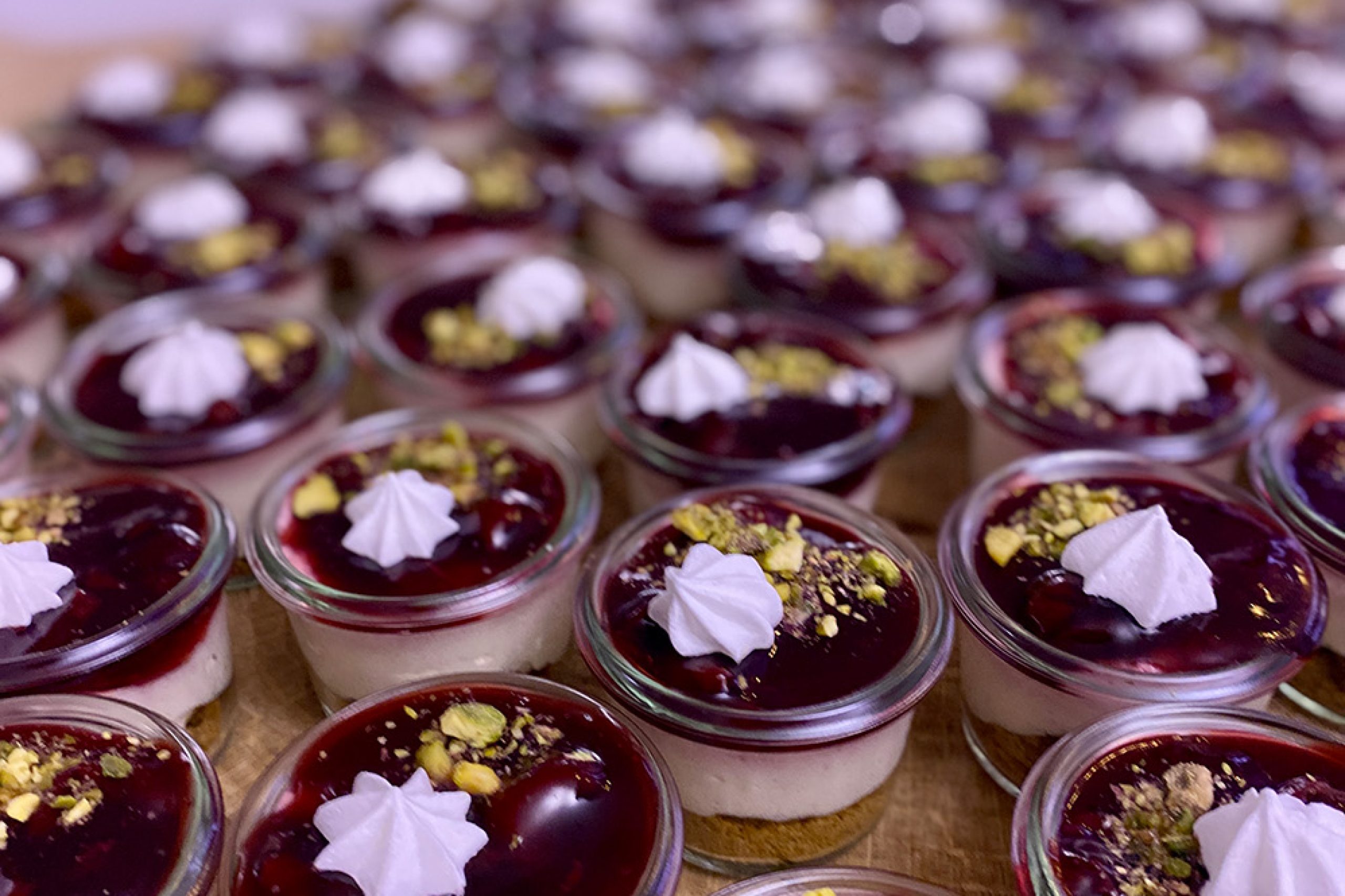 Små desserter i glas med bærkompot, flødeskum og pistacie fra den hjemmelavede dessertbuffet til Den Store Julefrokost hos Esbjerg Konference & Event.