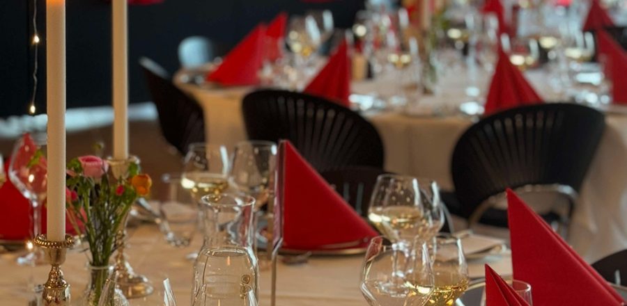 Røde servietter, levende lys og elegant opdækning sætter scenen for en festlig firmaaften med god mad, vin og hyggeligt samvær i Carlsberg Loungen.
