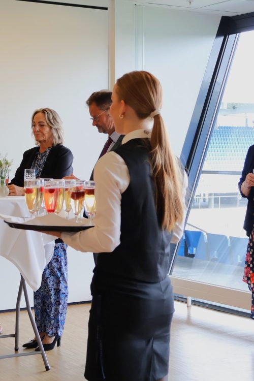 Tjener serverer velkomstdrink mens gæster snakker og smiler – en elegant start på en fejring