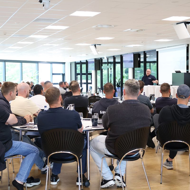 Deltagere lytter opmærksomt til oplæg under kursus eller konference i lyst lokale med store vinduer og moderne faciliteter.