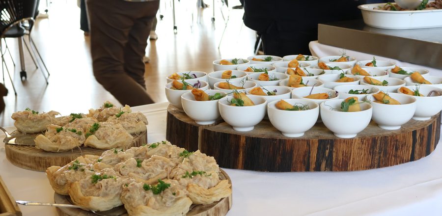 Buffetopstilling med små serveringer i skåle og tarteletter på træfade, klar til gæster.