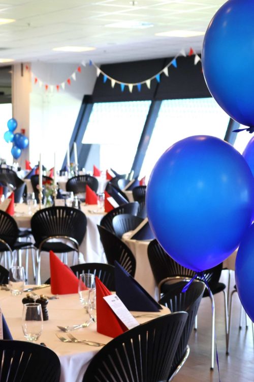 Festlig opdækning med blå balloner og farverige detaljer – klar til en festlig aften med god stemning og smil ved bordene.