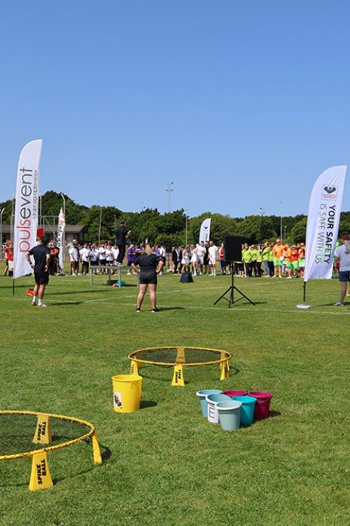 “Medarbejdere samles til teambuilding med farverige aktiviteter og udstyr arrangeret af Pulsevent på græsplænen ved atletikstadion i Esbjerg.