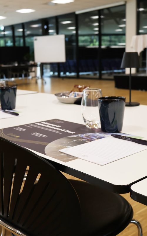 Lyst og indbydende mødelokale med borde dækket med glas, notesblokke og snacks klar til konference i Claus Sørensen Lounge hos Esbjerg Konference & Event.