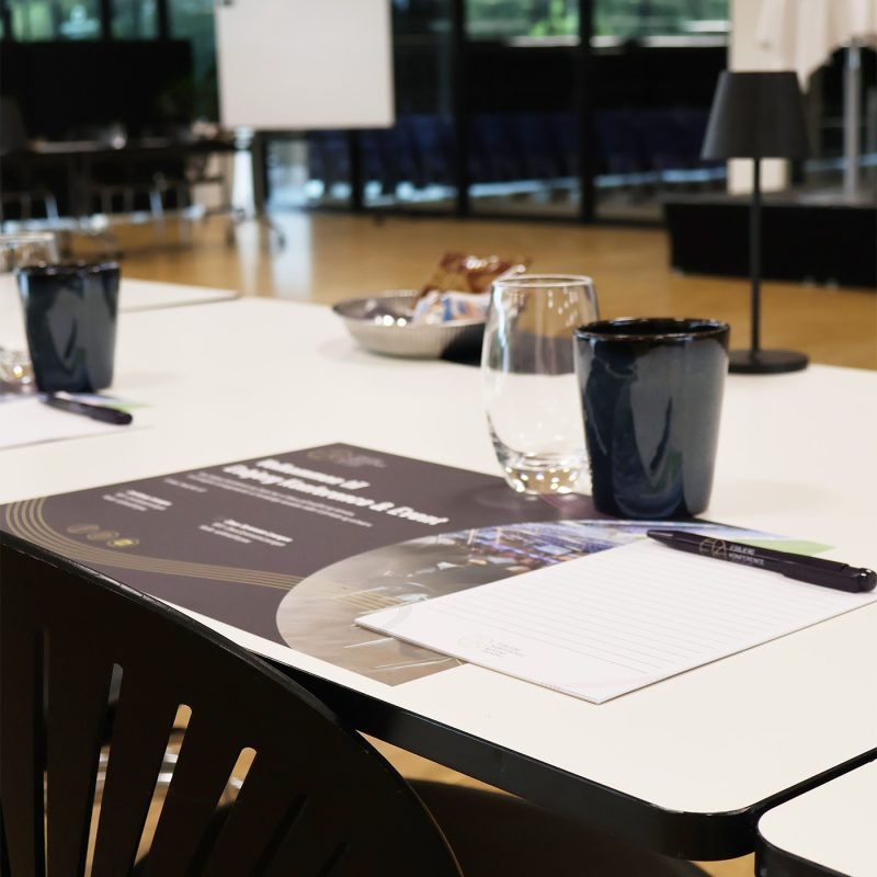 Lyst og indbydende mødelokale med borde dækket med glas, notesblokke og snacks klar til konference i Claus Sørensen Lounge hos Esbjerg Konference & Event.