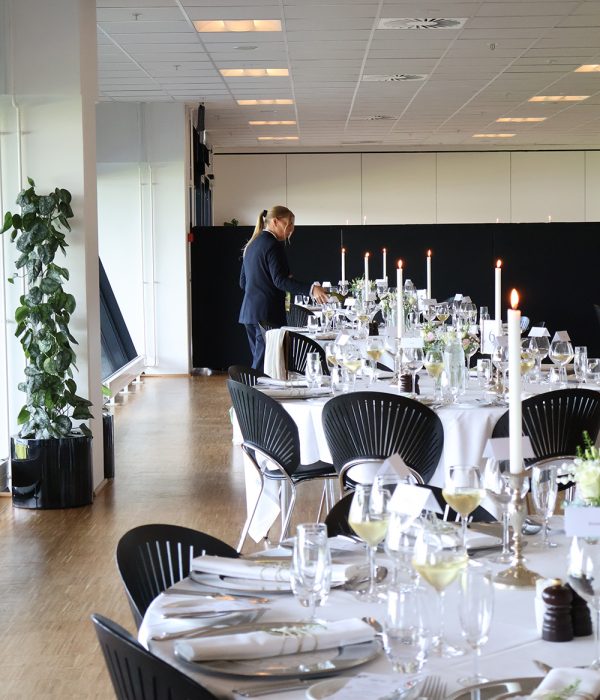 Personale gør klar til festligt dækkede borde med vin og stearinlys til bryllup hos Esbjerg Konference & Event i Carlsberg Loungen.
