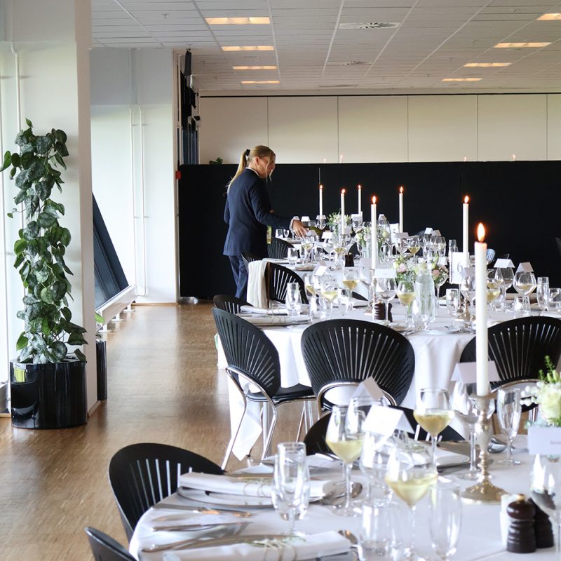 Personale gør klar til festligt dækkede borde med vin og stearinlys til bryllup hos Esbjerg Konference & Event i Carlsberg Loungen.