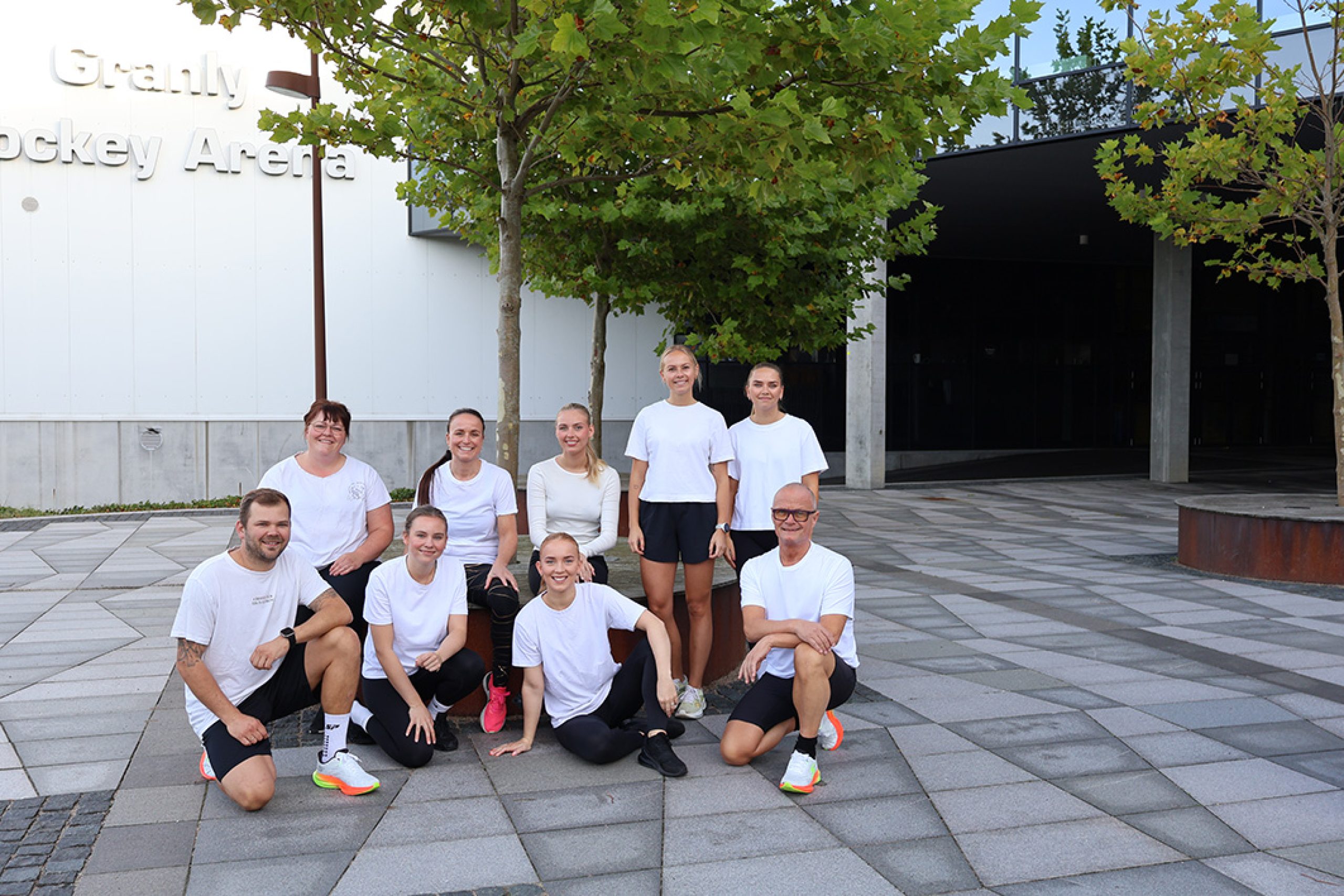 Deltagere i hvidt sportstøj fra Esbjerg Konference & Event klar til fællesløb Run Together foran Granly Hockey Arena.