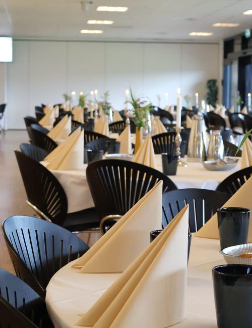 Carlsberg Loungen på Blue Water Arena dækket op med beige servietter, blomster, levende lys, småkager, kaffe og te.