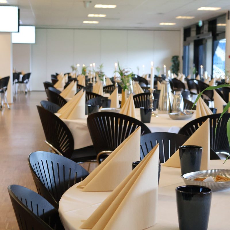 Carlsberg Loungen på Blue Water Arena dækket op med beige servietter, blomster, levende lys, småkager, kaffe og te.