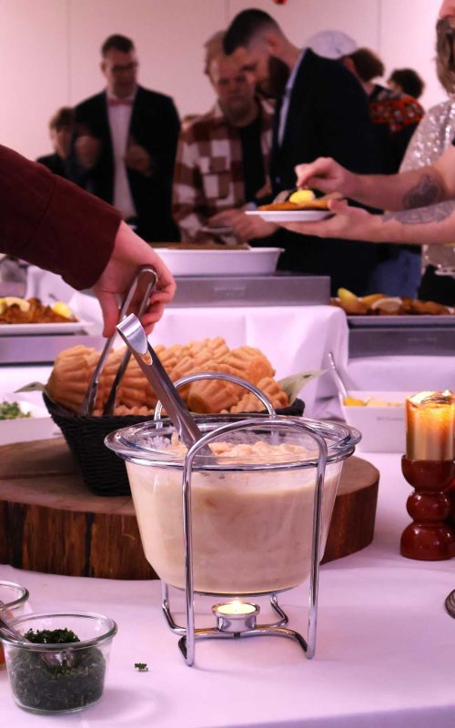 Gæster tager af buffeten til Den Store Julefrokost med tarteletter, fiskefilet og diverse julefrokostretter