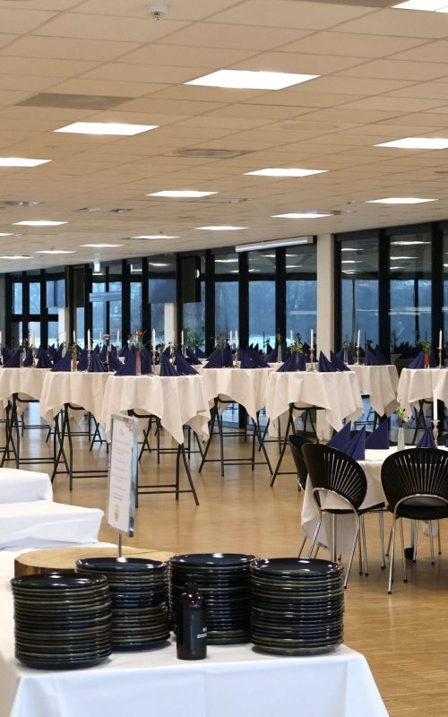 Lyst lokale i Esbjerg dækket op til reception med højborde, runde borde, buffet, pyntet med blomster, levende lys og blå servietter