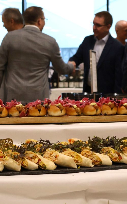 Gæster hilser bagved buffet med gourmet hotdogs og andre små retter til reception