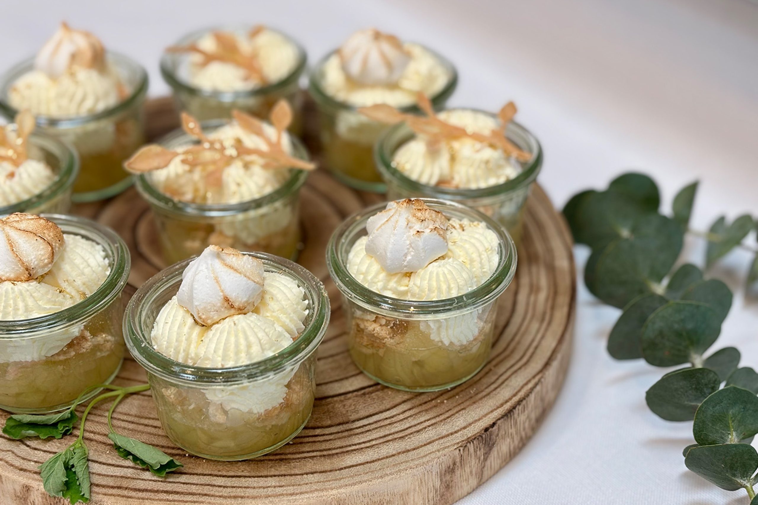 Små glas med klassisk æblekage toppet med flødeskum, bagt marengs og pynt – smukt anrettet på træfad af husets egen konditor.