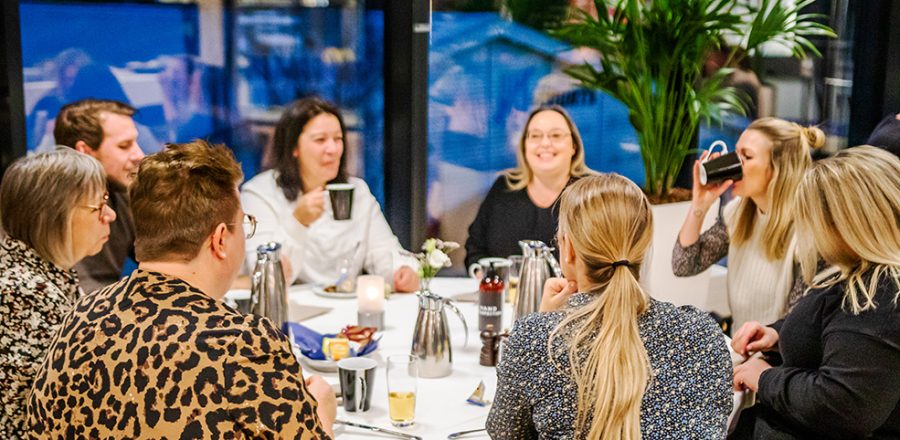 Gæster nyder kaffe og samtale omkring et opdækket bord i hyggelige omgivelser i Claus Sørensen Lounge hos Esbjerg Konference & Event.