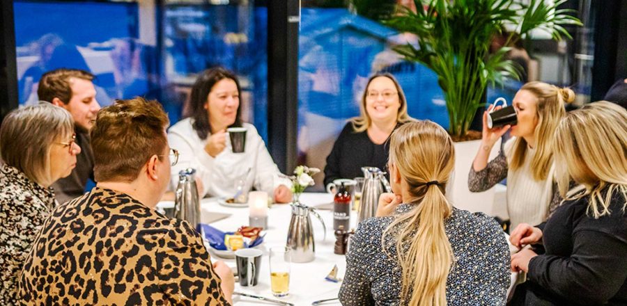 Gæster nyder kaffe og samtale omkring et opdækket bord i hyggelige omgivelser i Claus Sørensen Lounge hos Esbjerg Konference & Event.