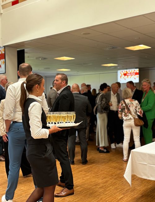 Servitrice serverer velkomstbobler for gæster ved et festligt arrangement i loungen på Blue Water Arena.