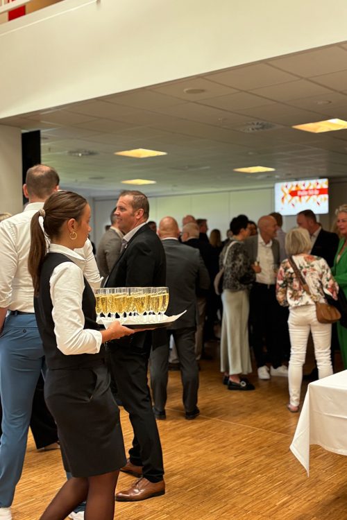 Servitrice serverer velkomstbobler for gæster ved et festligt arrangement i loungen på Blue Water Arena.