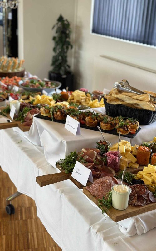 Indbydende tapasbuffet dækket op med charcuteri, oste, bruschetta og friskbagt brød – klar til gæsterne ved et elegant arrangement.