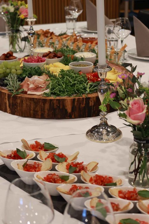 Smukt dækket bord med tapas, små forretter og blomsterdekorationer – klar til hyggelige timer og god stemning.