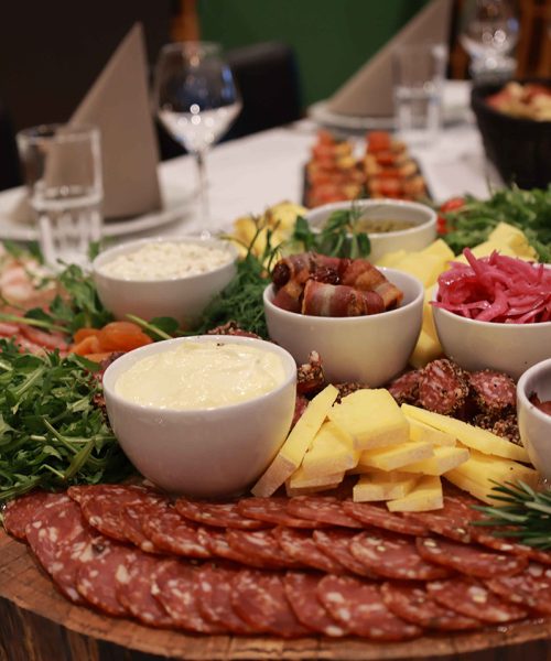 Et overdådigt tapasbræt fyldt med pølser, oste, frugt, grønt og små skåle med dips – anrettet med kærlighed til detaljen af Esbjerg Konference & Events eget køkken.
