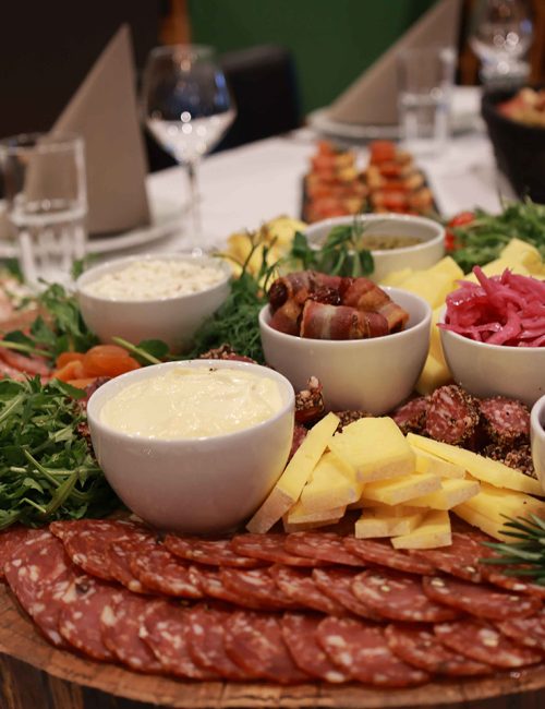 Et overdådigt tapasbræt fyldt med pølser, oste, frugt, grønt og små skåle med dips – anrettet med kærlighed til detaljen af Esbjerg Konference & Events eget køkken.